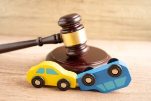 Demanda por accidente automovilístico y seguro, juez con martillo y modelo de automóvil.